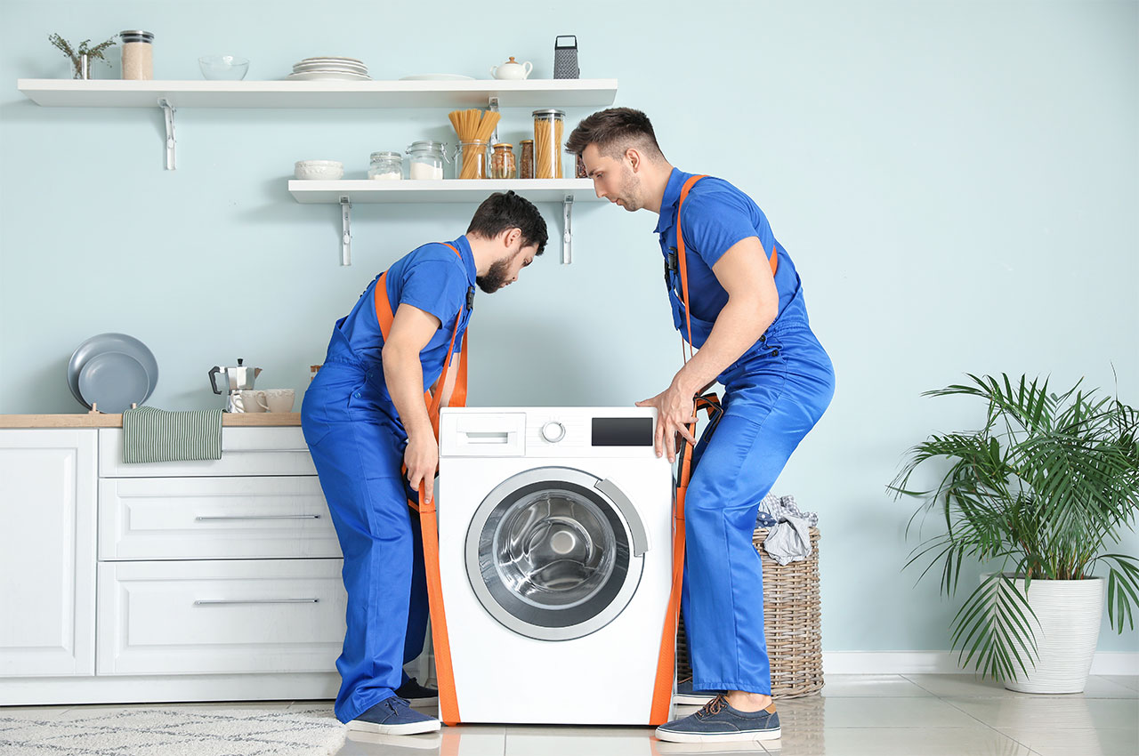 two men in overalls moving a washing machine